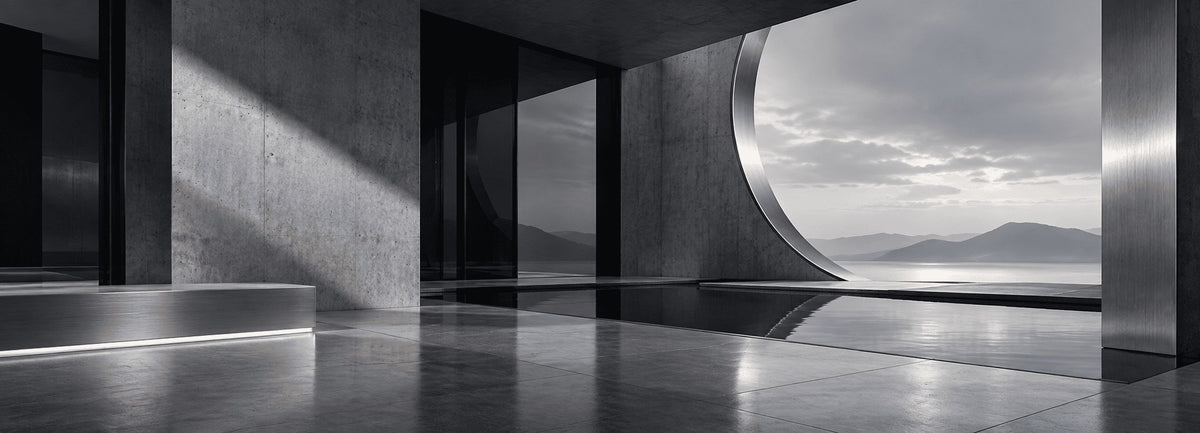 Minimalist concrete architecture with curved walls, reflected light and distant mountains beside water.