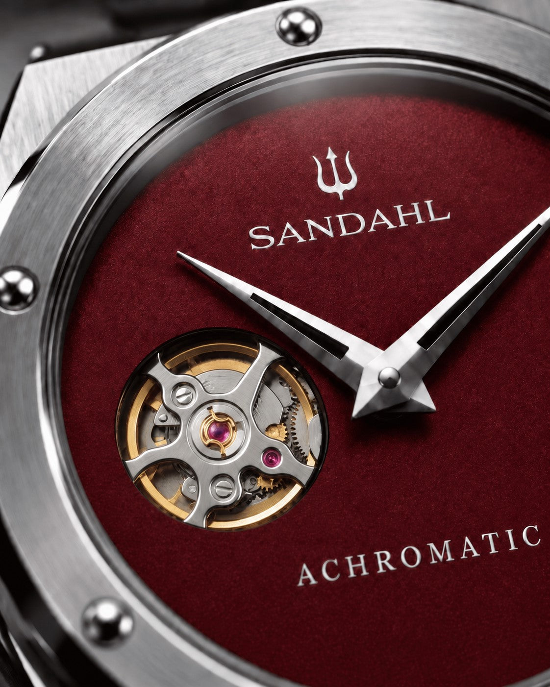 Close-up of the red SANDAHL ACHROMATIC Crimson dial, showing the open-heart aperture and polished hands.