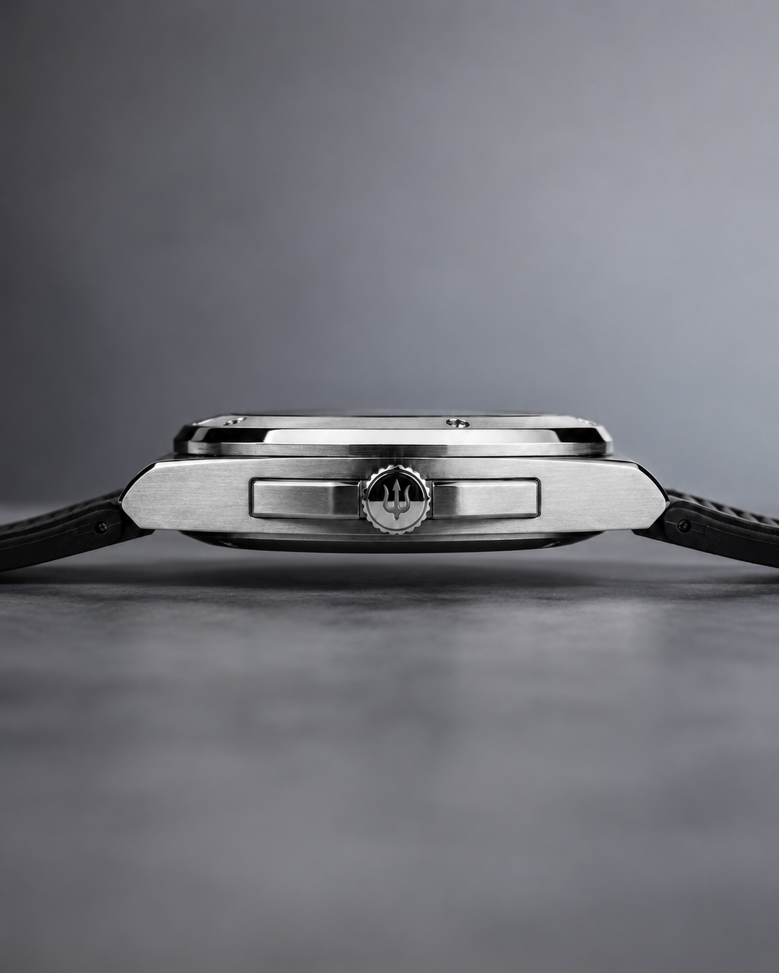 Side profile of the SANDAHL ACHROMATIC steel case with a black rubber strap and trident-engraved crown.