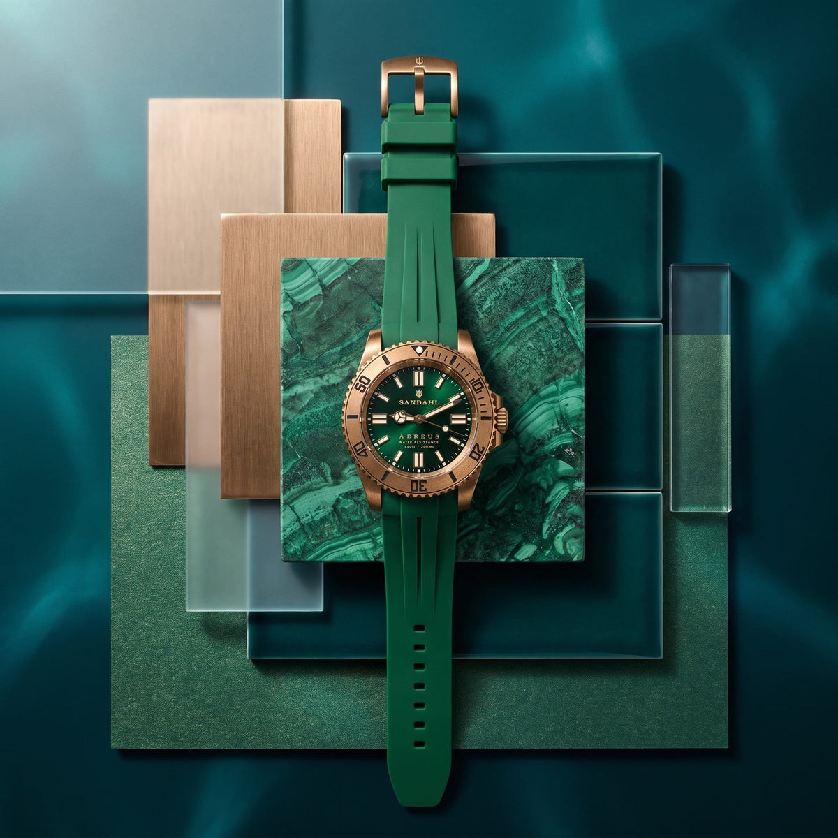 SANDAHL AEREUS Emerald Current bronze watch with green dial and rubber strap on layered green stone, metal and glass samples.