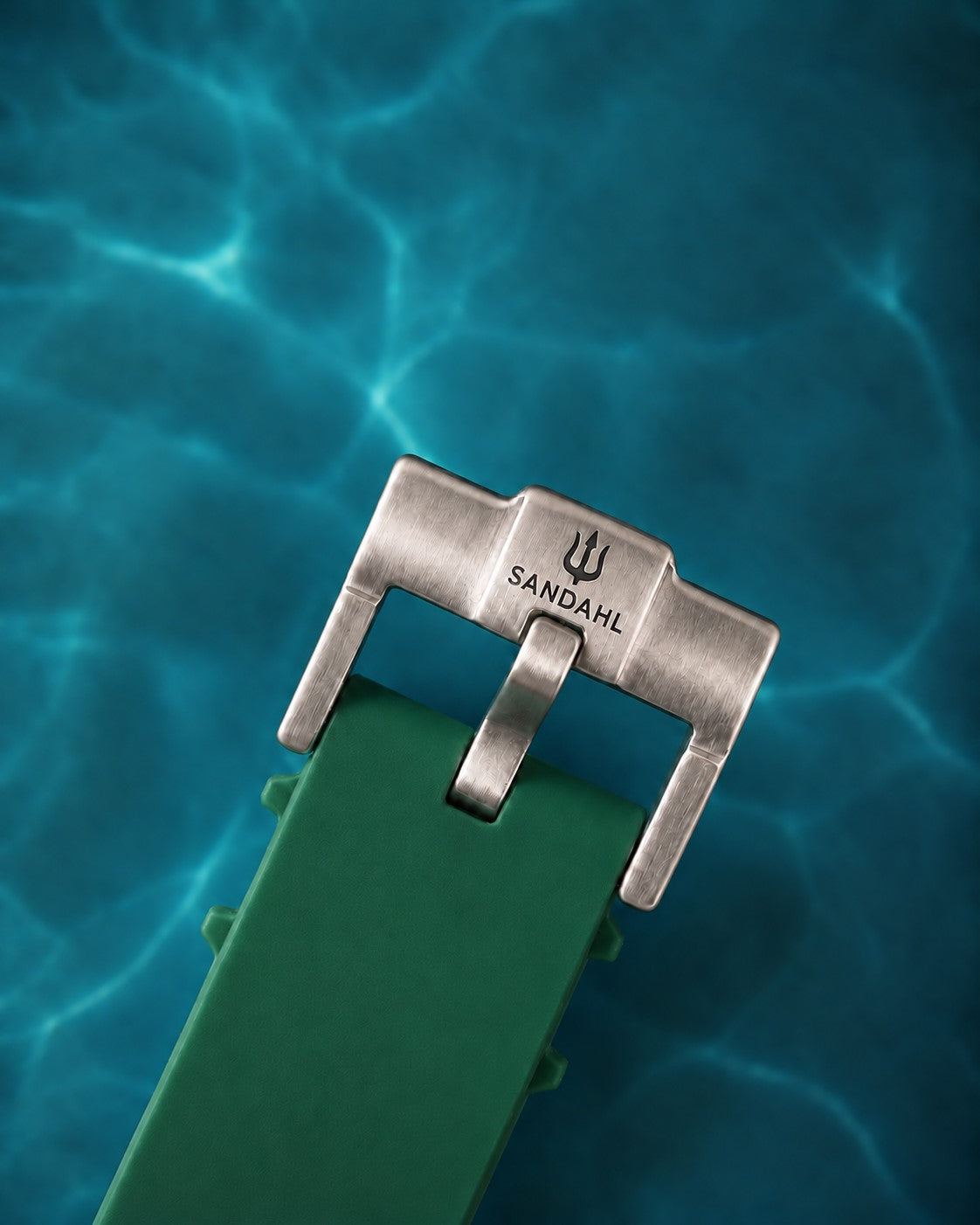 Close-up of the SANDAHL-engraved steel buckle and green rubber strap for AEREUS Emerald Current.