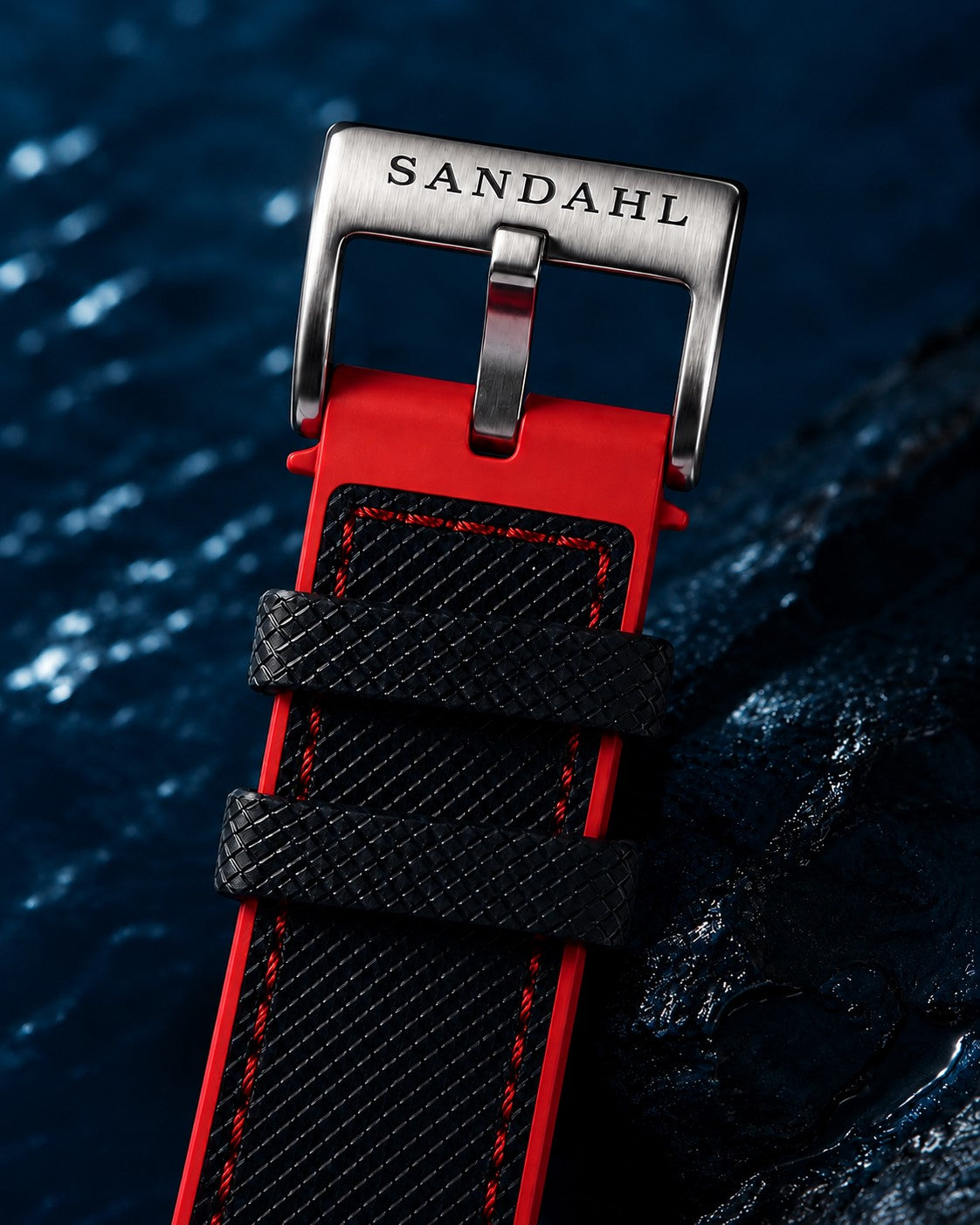 Close-up of the SANDAHL-engraved buckle and black and red textured strap on CENTURION Signal Red.