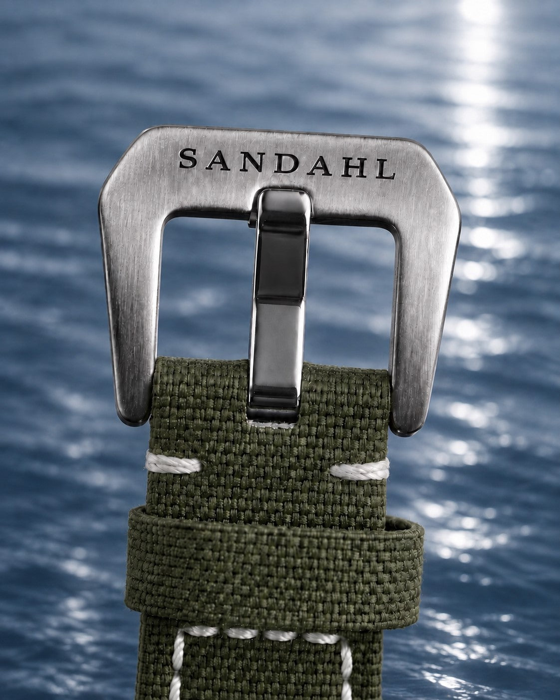 Close-up of the engraved steel buckle and stitched fabric strap on SANDAHL SHALLOW Archipelago Green.