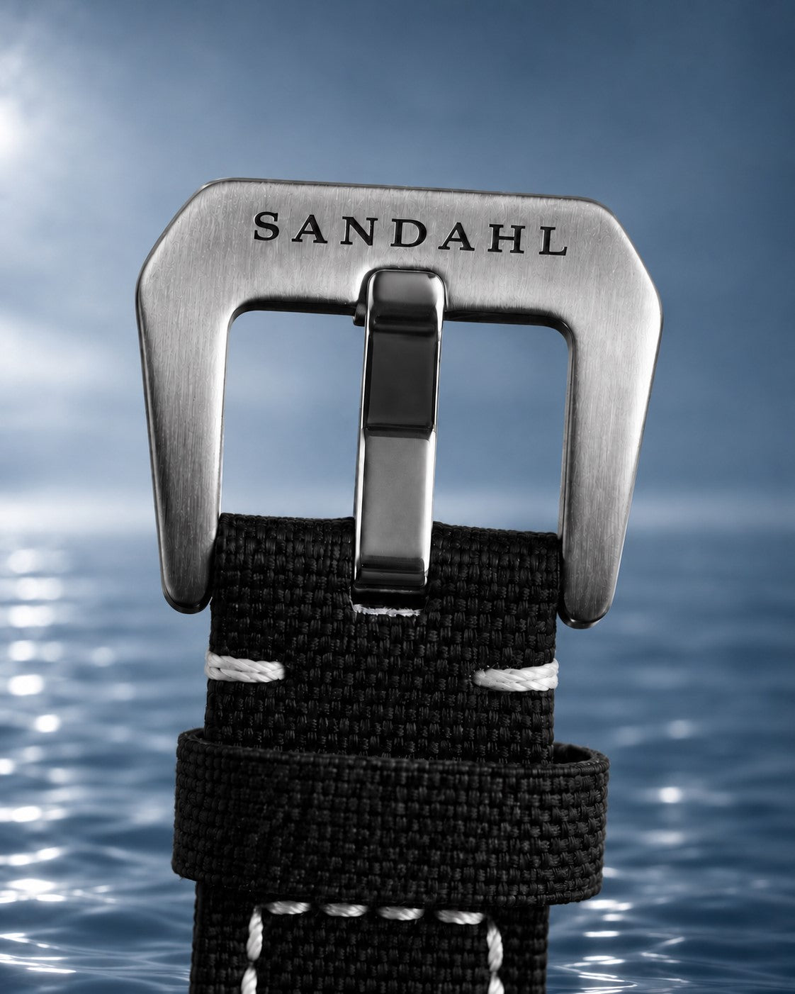 Close-up of the engraved steel buckle and stitched fabric strap on SANDAHL SHALLOW Granite Grey.
