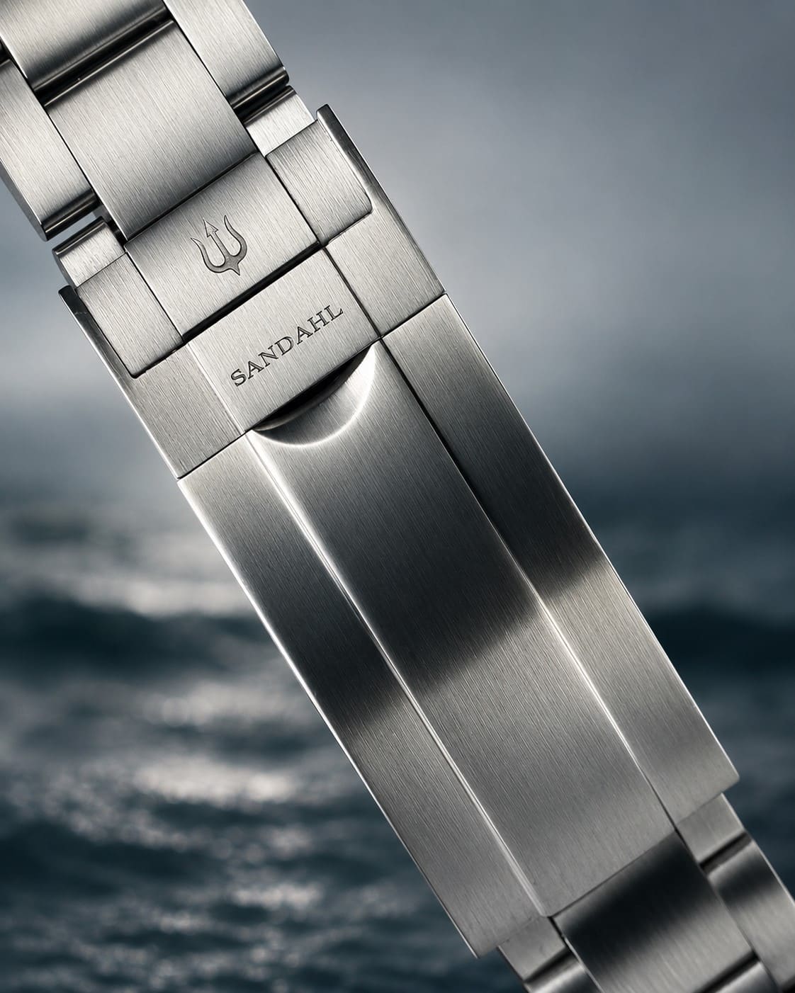 Close-up of a SANDAHL SHALLOW steel bracelet clasp engraved with SANDAHL and the trident.