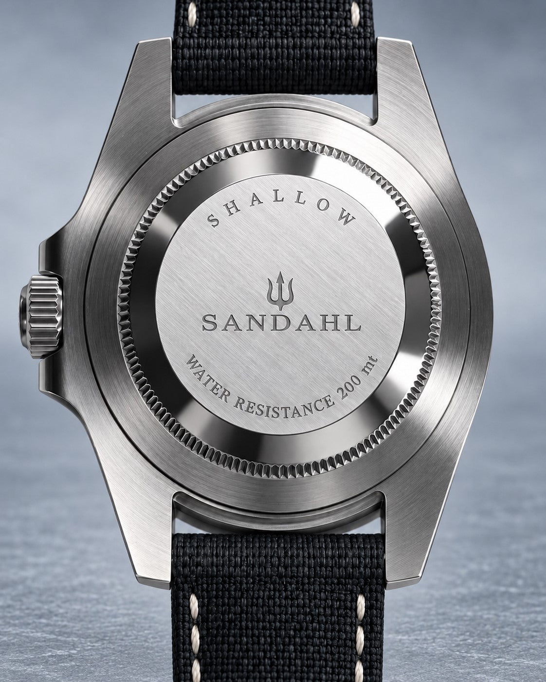 Rear view of a SANDAHL SHALLOW watch with its engraved steel caseback and black stitched fabric strap.