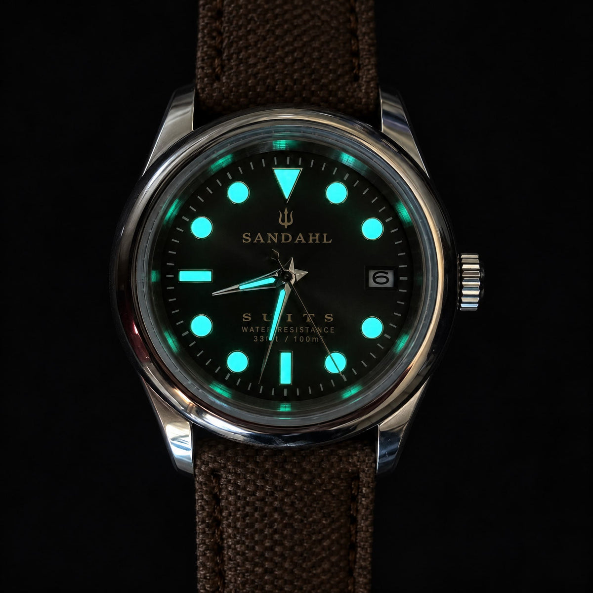 SANDAHL SUITS watch with luminous hands and hour markers, shown on a brown fabric strap against a dark background.