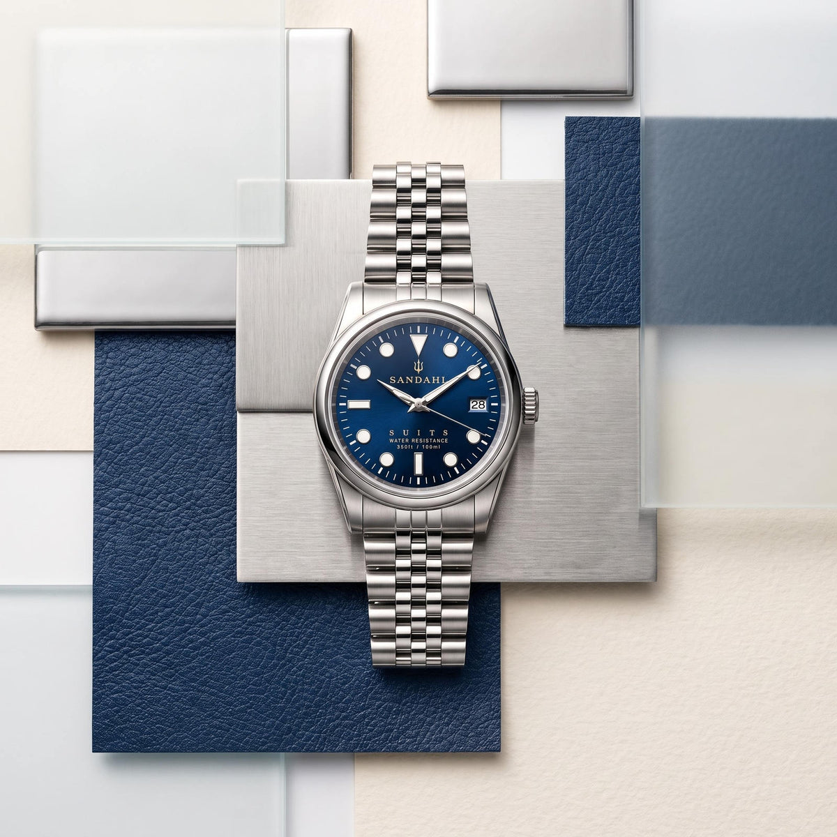 SANDAHL SUITS with a Midnight Navy dial and Jubilee bracelet, arranged with blue leather, brushed steel and glass panels.