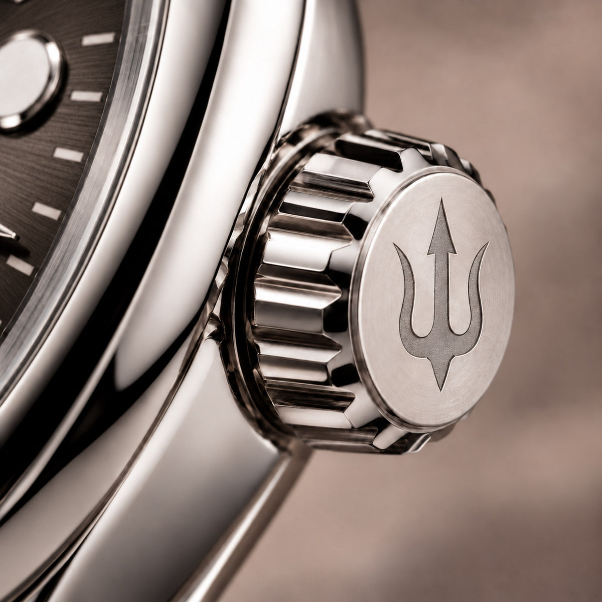 Close-up of the SUITS Savile Taupe stainless steel crown with its engraved trident, fluted edges and taupe dial.