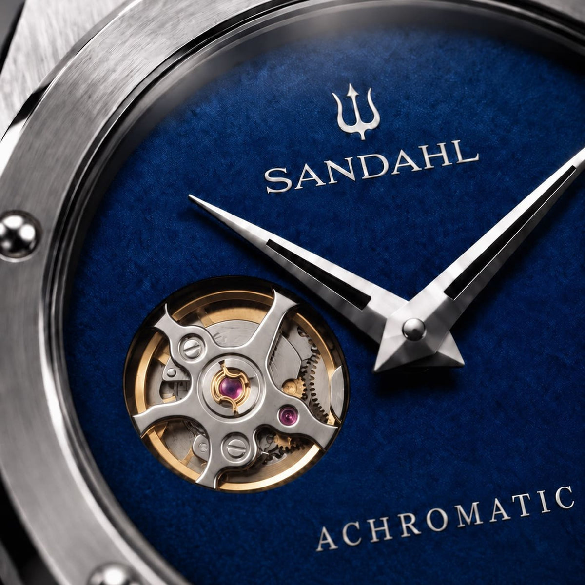 Close-up of the blue SANDAHL ACHROMATIC Cobalt dial, open-heart aperture, polished hands and trident.