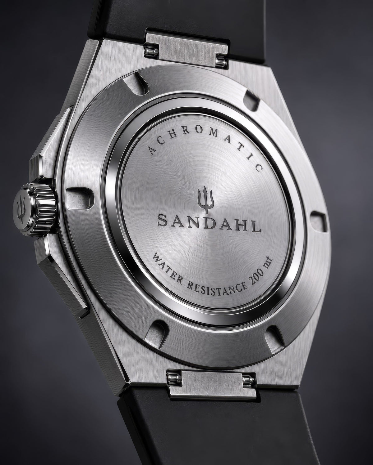 Rear view of the SANDAHL ACHROMATIC with a black rubber strap and brushed steel caseback engraved with the brand and trident.
