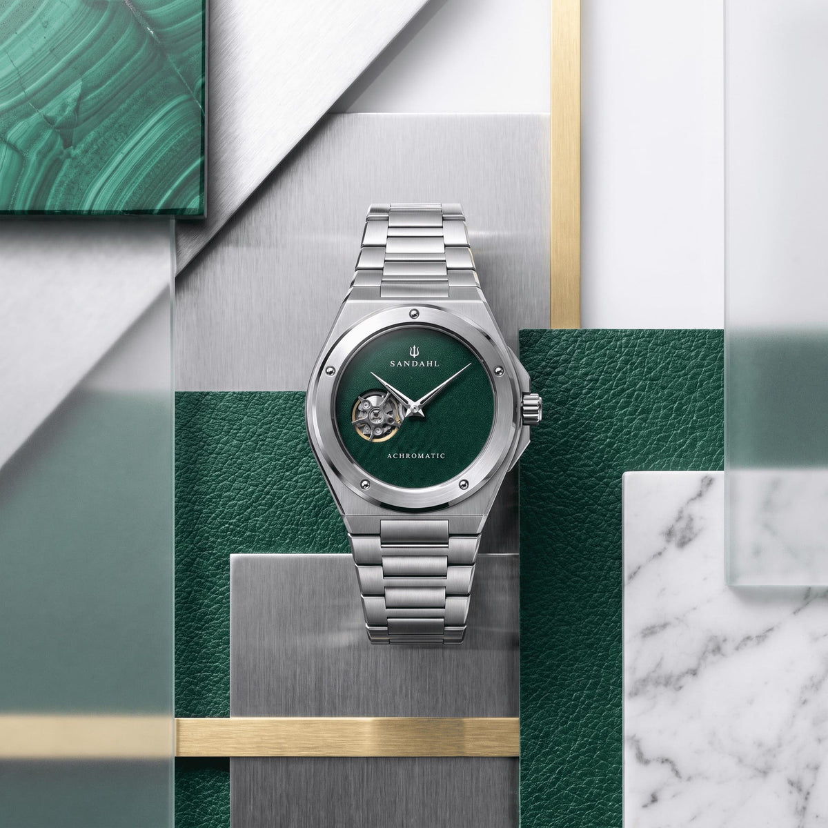 SANDAHL ACHROMATIC Petrol with a steel bracelet, arranged among green, silver and white material samples.