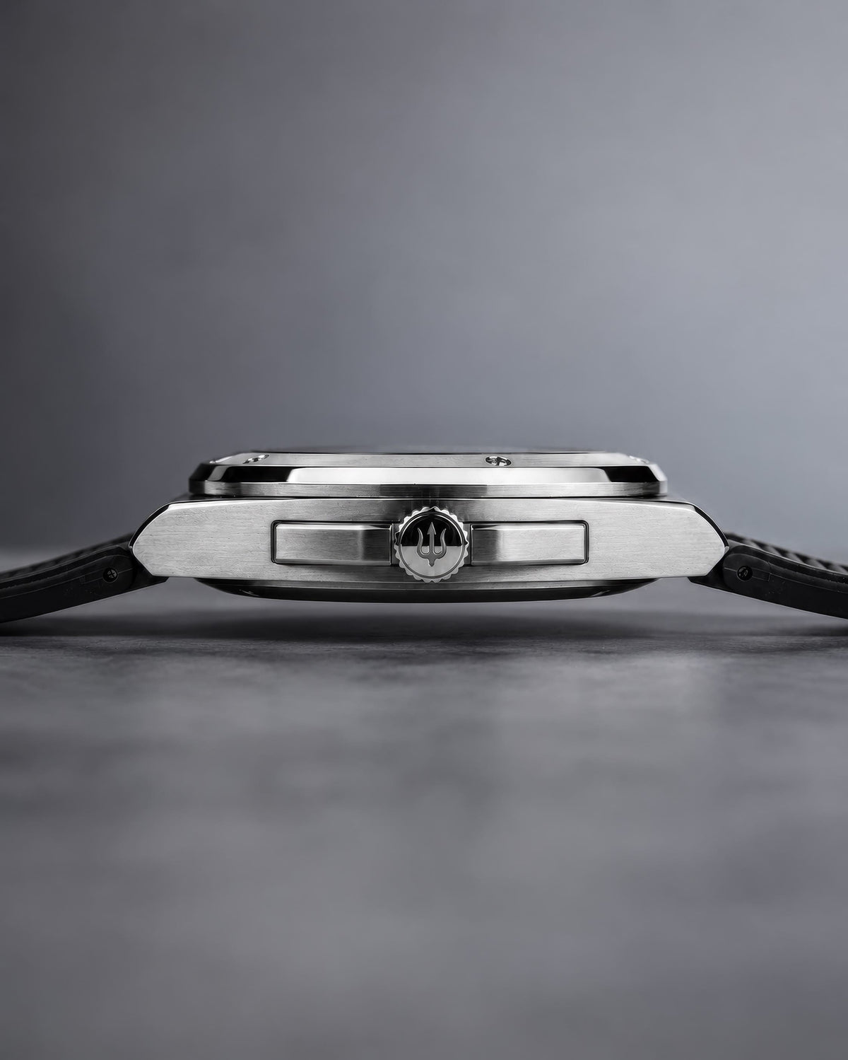 Side profile of the SANDAHL ACHROMATIC steel case with a black rubber strap and trident-engraved crown.