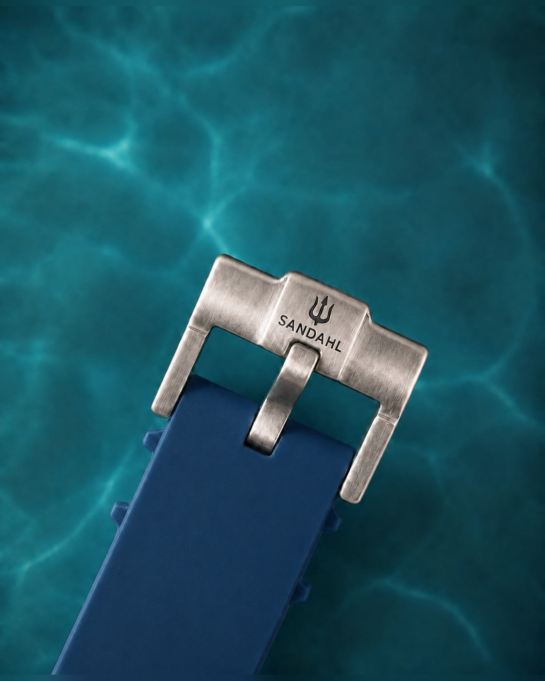 Close-up of the SANDAHL-engraved steel buckle and navy blue rubber strap for AEREUS Abyss Blue.