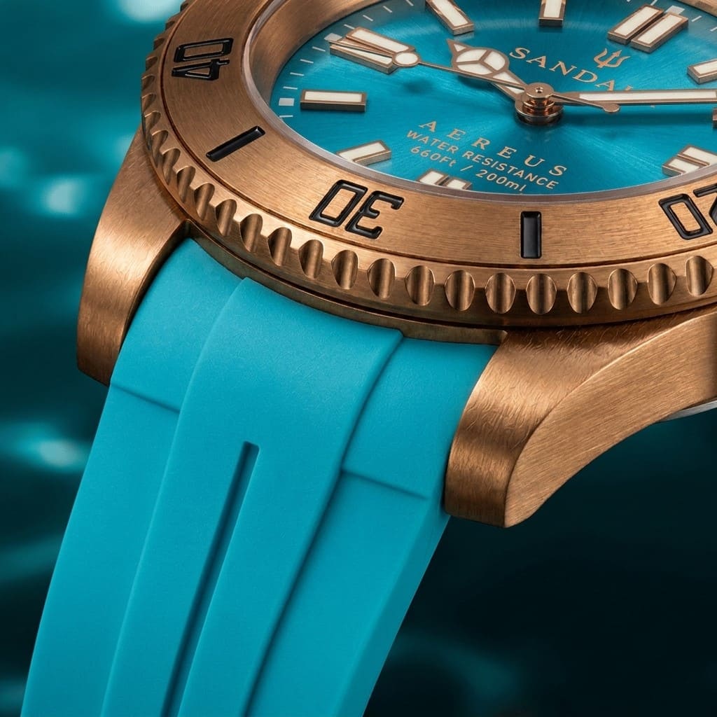 Close-up of the SANDAHL AEREUS Glacial aqua brushed bronze case, scalloped dive bezel and black rubber strap.