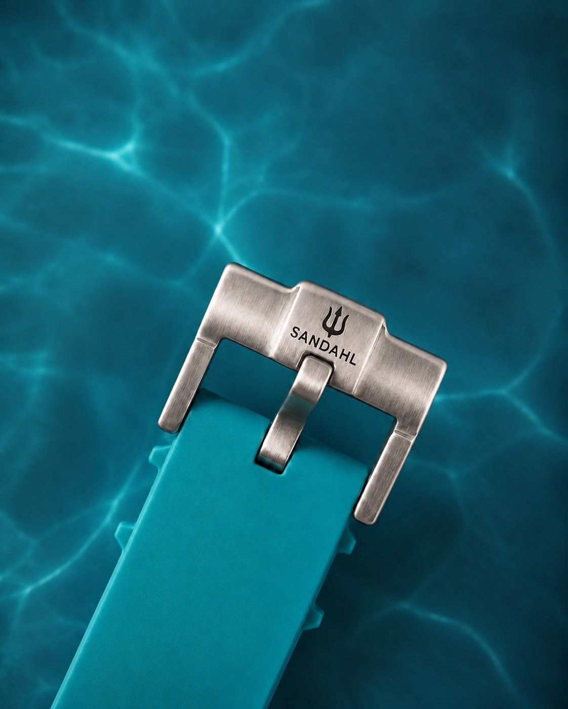 Close-up of the SANDAHL-engraved steel buckle and aqua rubber strap for AEREUS Glacial Aqua.