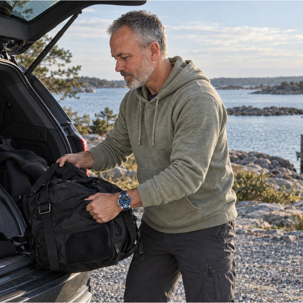 Man wearing a SANDAHL CENTURION Abyss Blue watch while unloading diving equipment from an SUV beside the Swedish archipelago.