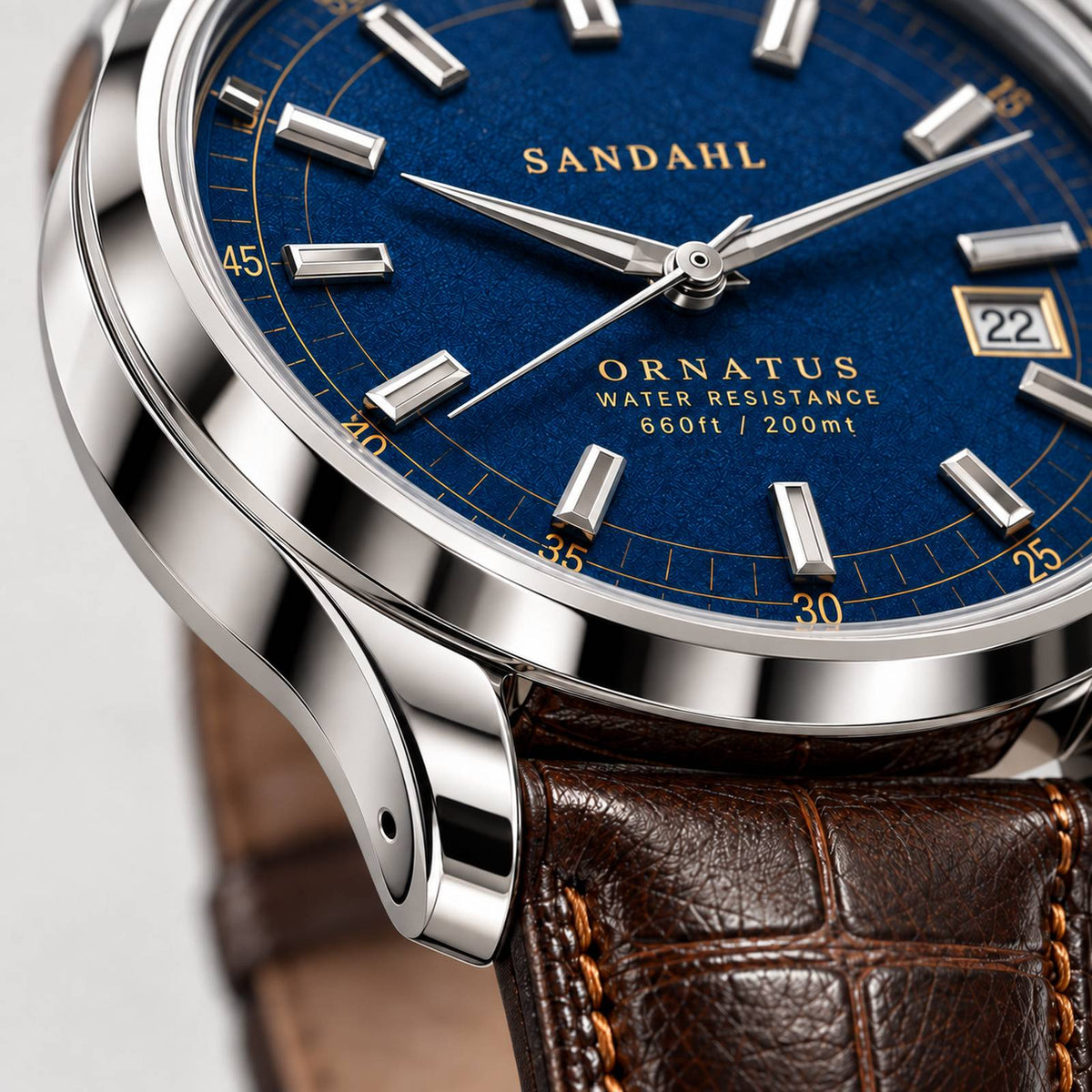 Close-up of the polished steel case and rounded lugs of SANDAHL ORNATUS Cobalt, with a blue textured dial and brown leather strap.