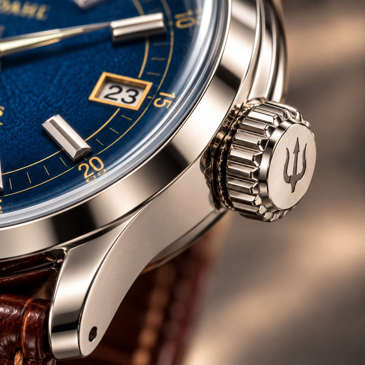 Close-up of the grooved steel crown with engraved trident on SANDAHL ORNATUS Cobalt, beside the blue dial and polished case.