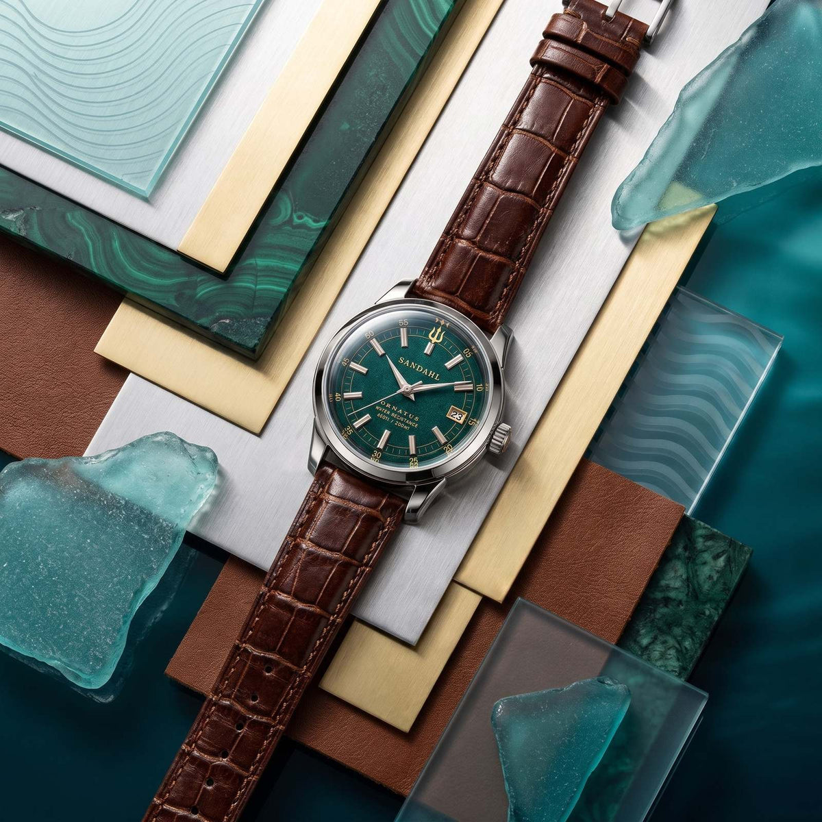 SANDAHL ORNATUS Malachite with a green dial and brown crocodile-pattern leather strap, arranged with green stone, glass and metal material samples.