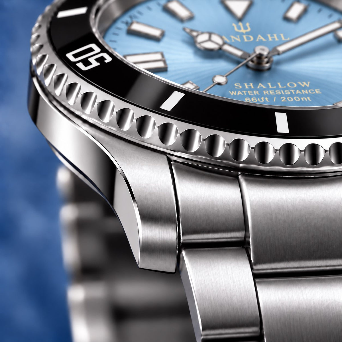 Macro view of the SANDAHL SHALLOW Glacial Blue steel case and bracelet, with a black dive bezel and ice-blue dial.