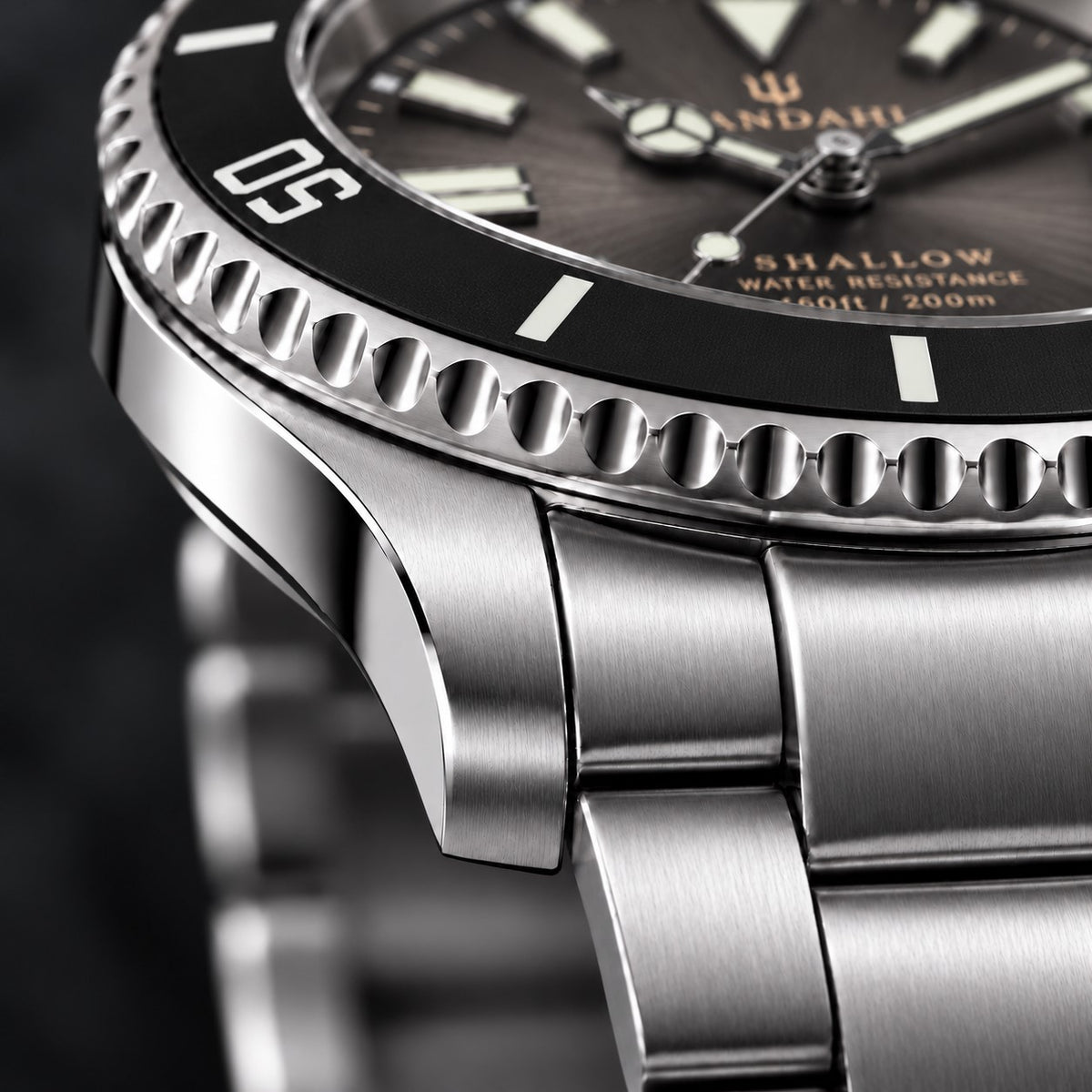 Macro view of the SANDAHL SHALLOW Granite Grey steel case and bracelet, with a black dive bezel and grey dial.