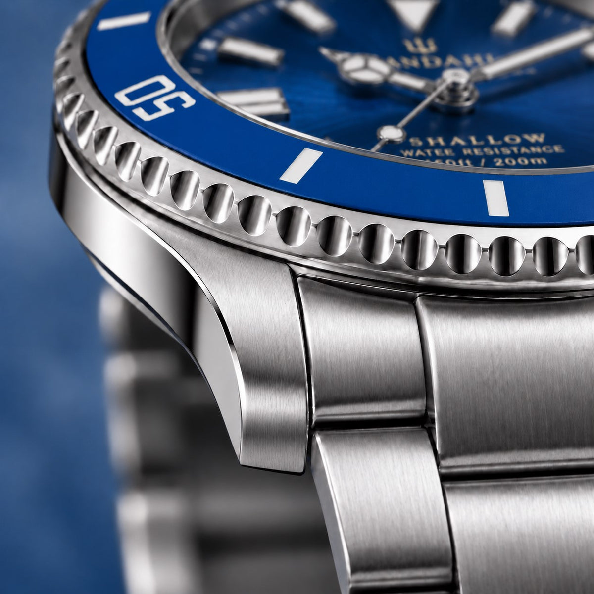 Macro view of the SANDAHL SHALLOW Kattegatt Blue steel case and bracelet, with a blue dive bezel and blue dial.