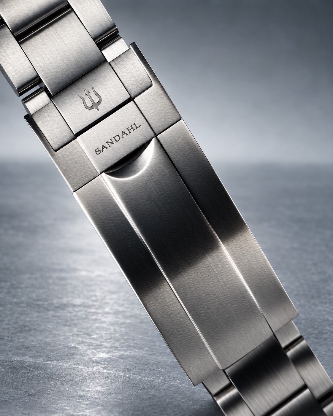 Close-up of a SANDAHL SHALLOW steel bracelet clasp engraved with SANDAHL and the trident.