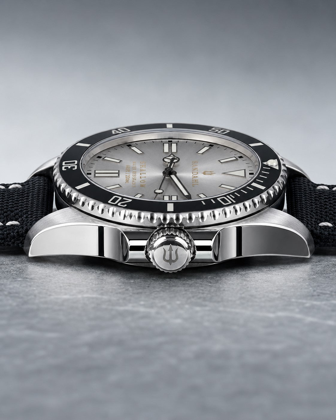 Low angled view of SANDAHL SHALLOW Sea Mist Silver, showing the dial, dive bezel and stitched fabric strap.
