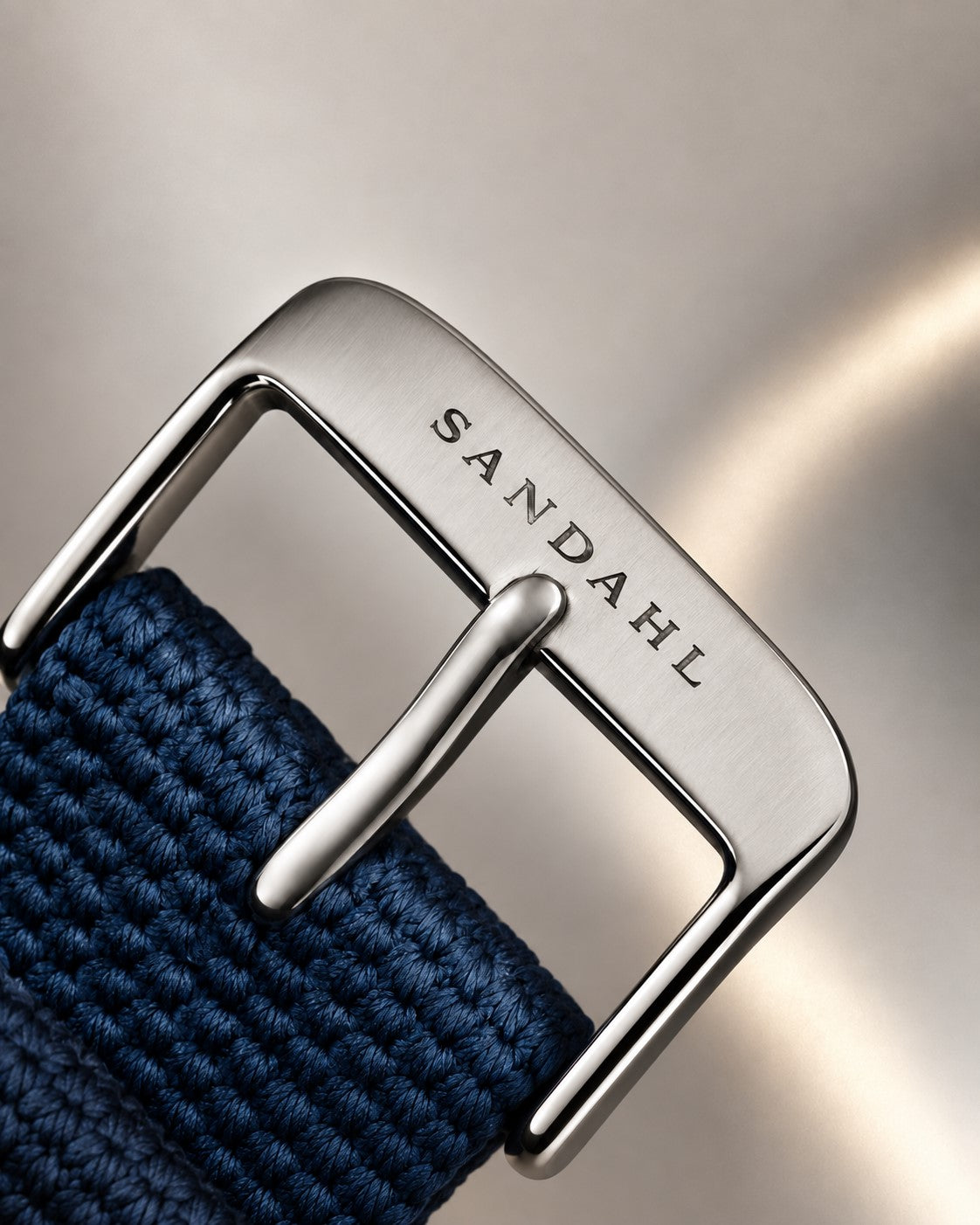 Close-up of the SANDAHL-engraved steel buckle and blue textile strap for SUITS.