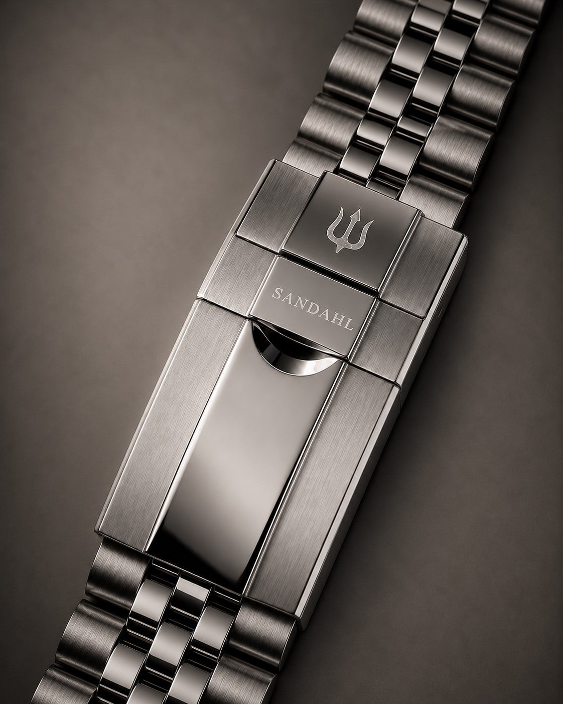 Close-up of the SANDAHL SUITS steel bracelet clasp engraved with SANDAHL and the trident.