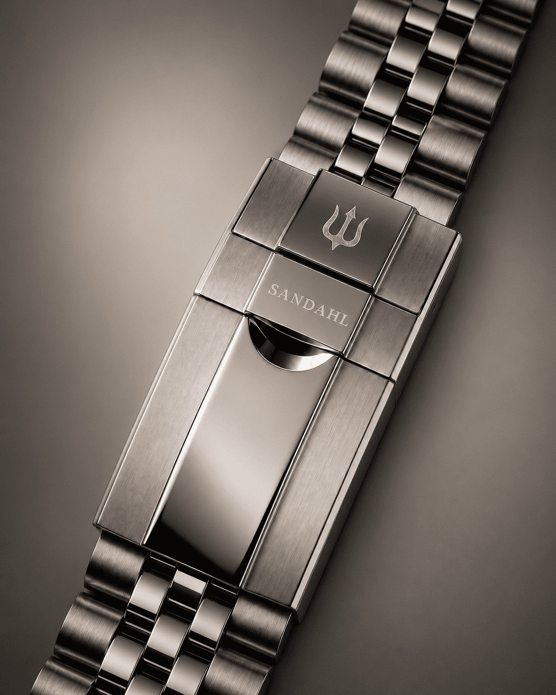 Close-up of the SANDAHL SUITS steel bracelet clasp engraved with SANDAHL and the trident.